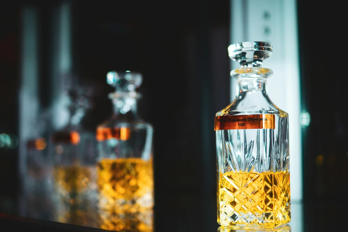 Crystal decanter of amber whiskey with more bottles softly blurred behind it